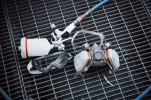 Spray paint gun and respirator mask used in automotive spray painting