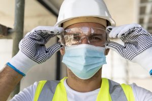 Construction worker wearing safety glasses and a hard hat on a building site